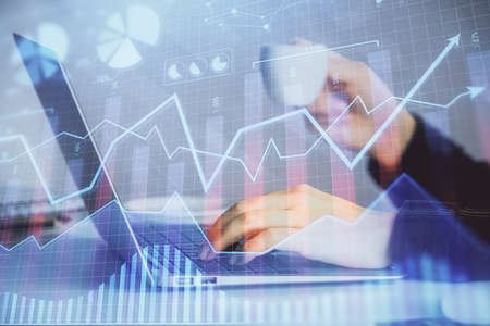 Double exposure of businesswoman hands typing on computer and forex graph hologram drawing....