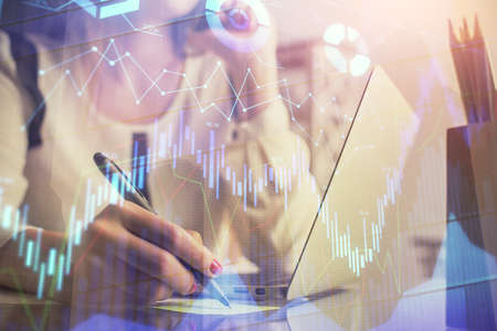 Double exposure of woman hands typing on computer and financial graph hologram drawing. Stock market...