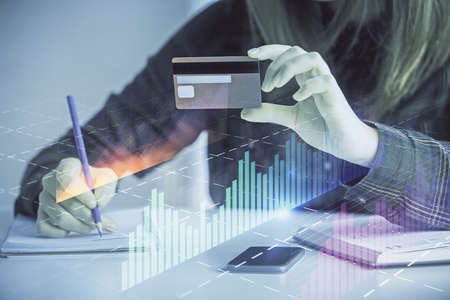 Double exposure of woman on-line shopping holding a credit card and financial graph drawing. Stock market E-commerce concept.の写真素材