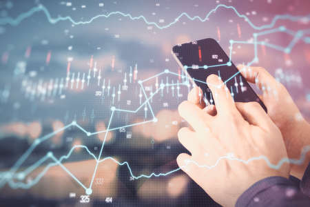 Double exposure of man's hands holding and using a digital device and forex graph drawing. Financial...