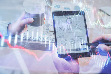 Double exposure of man's hands holding and using a phone and financial chart drawing. Market...