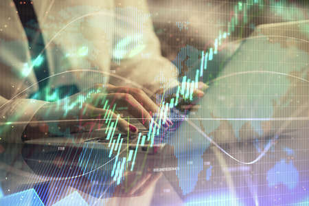Double exposure of businesswoman hands typing on computer and financial graph hologram drawing....