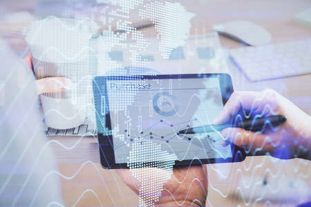 Double exposure of man's hands holding and using a phone and financial chart drawing. Market...