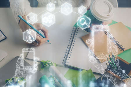 Tech theme hologram over woman's hands taking notes background. Concept of hightech. Double exposure