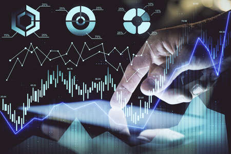 Double exposure of man's hands holding and using a digital device and forex graph drawing. Financial...