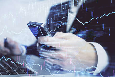 Multi exposure of man's hands holding and using a digital phone and forex graph drawing. Financial...