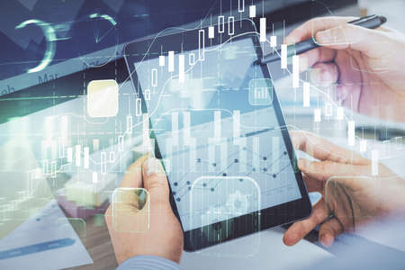 Double exposure of man's hands holding and using a phone and financial chart drawing. Market...