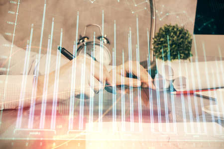 Double exposure of man's hands holding and using a phone and financial graph drawing. Analysis...