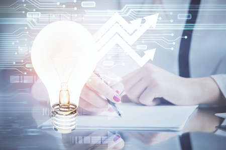 Bulb hologram over hands taking notes background. Concept of idea. Double exposureの写真素材