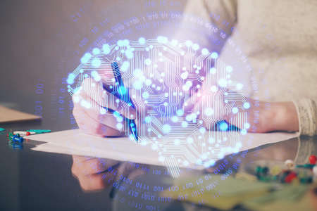 Double exposure of woman's writing hand on background with brain hud. Concept of learning.の写真素材