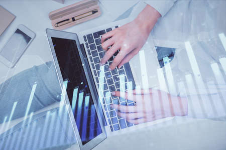 Double exposure of woman hands working on computer and forex graph hologram drawing. Top View....