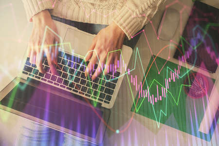 Double exposure of woman hands working on computer and forex chart hologram drawing. Top View....