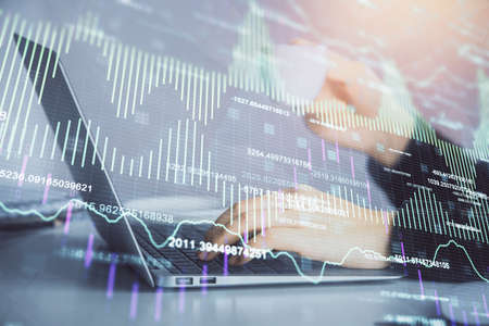 Double exposure of businesswoman hands typing on computer and forex graph hologram drawing....