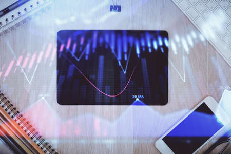 Double exposure of forex graph hologram over desktop with phone. Top view. Mobile trade platform concept.の写真素材