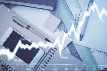 Multi exposure of forex graph hologram over desktop with phone. Top view. Mobile trade platform...