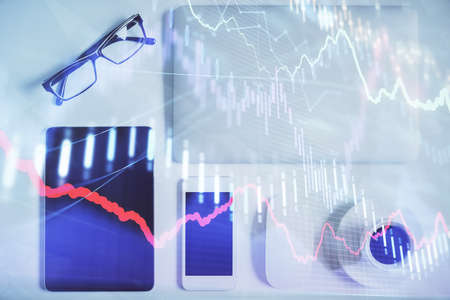 Double exposure of forex chart hologram over desktop with phone. Top view. Mobile trade platform...