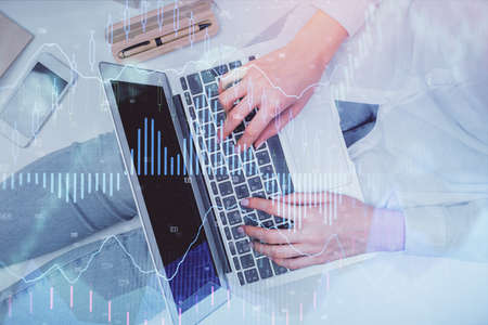 Double exposure of woman hands working on computer and forex graph hologram drawing. Top View....