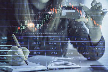 Double exposure of woman on-line shopping holding a credit card and financial graph drawing. Stock...