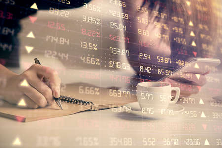 Double exposure of forex graph sketch hologram and woman holding and using a mobile device. Stock...