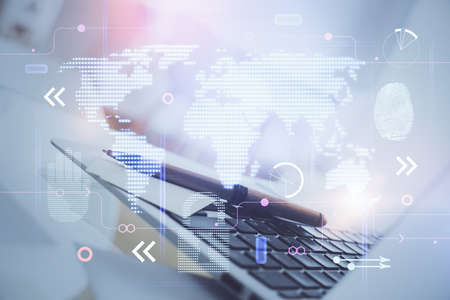 Double exposure of desktop with computer and world map hologram. International data network concept.の写真素材