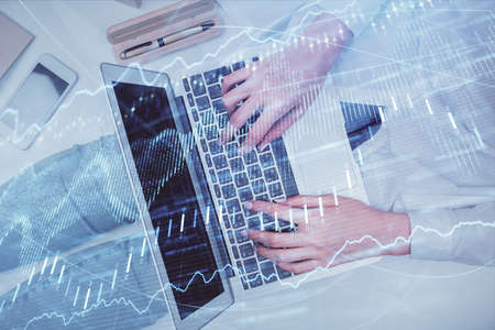 Double exposure of woman hands working on computer and forex graph hologram drawing. Top View....