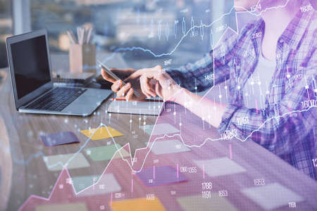 Double exposure of businesswoman hands typing on computer and forex graph hologram drawing....