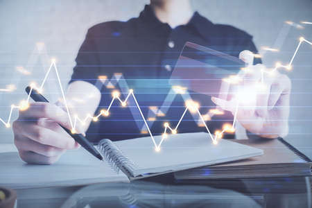 Double exposure of man hands holding a credit card and Forex graph drawing. Stock trading and...