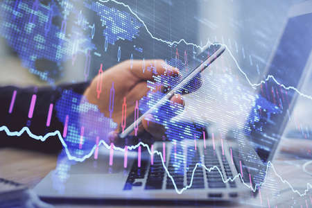 Double exposure of man's hands holding and using a phone and financial graph drawing. Analysis...