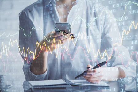 Double exposure of forex chart sketch hologram and woman holding and using a mobile device....
