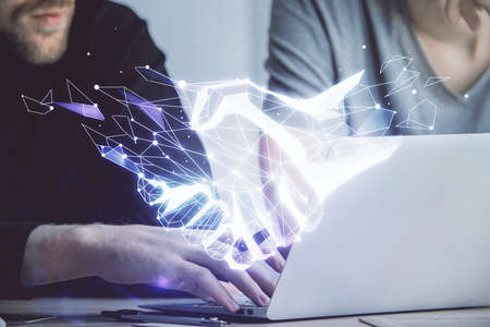 Handshake hologram drawing with businessman working on computer on background. Double exposure.