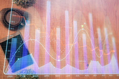 Multi exposure of financial chart hologram over desktop with phone. Top view. Mobile trade platform...