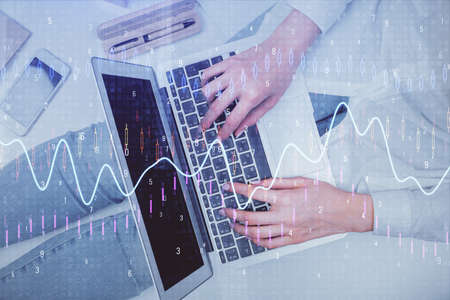 Double exposure of woman hands working on computer and forex graph hologram drawing. Top View....