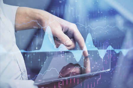 Double exposure of man's hands holding and using a digital device and forex graph drawing. Financial...