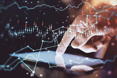 Double exposure of man's hands holding and using a digital device and forex graph drawing. Financial market concept.の写真素材