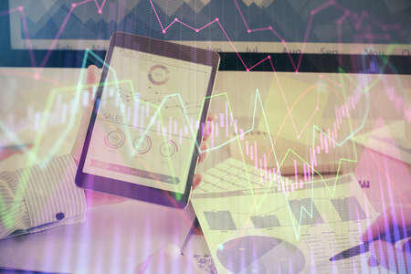 Double exposure of man's hands holding and using a digital device and forex graph drawing. Financial...