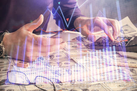 Double exposure of man's hands holding and using a digital device and forex graph drawing. Financial market concept.の写真素材