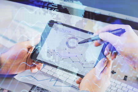 Double exposure of man's hands holding and using a phone and financial chart drawing. Market...