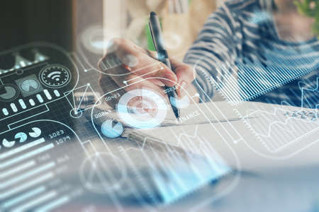 Tech theme hologram over woman's hands taking notes background. Concept of hightech. Double exposureの写真素材