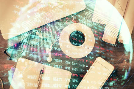 Business theme hologram drawings over computer on the desktop background. Top view. Multi exposure....