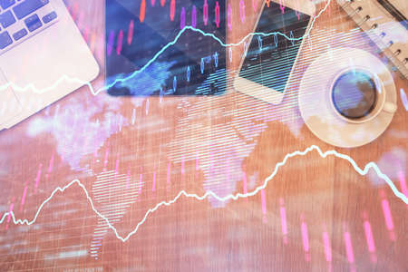 Double exposure of financial chart hologram over desktop with phone. Top view. Mobile trade platform concept.の写真素材