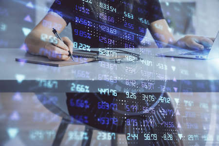 Double exposure of businesswoman hands typing on computer and forex chart hologram drawing....