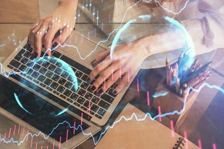 Double exposure of woman hands typing on computer and forex chart hologram drawing. Stock market...
