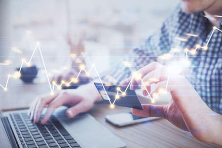 Double exposure of man hands holding a credit card and Forex graph drawing. Stock trading and...
