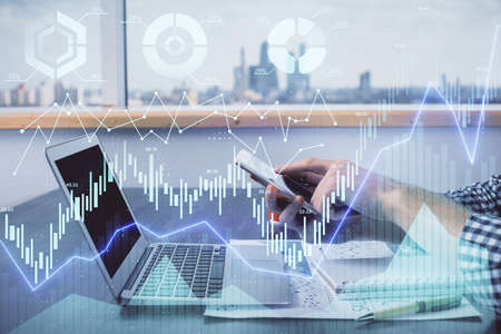 Double exposure of man's hands holding and using a digital device and forex graph drawing. Financial...