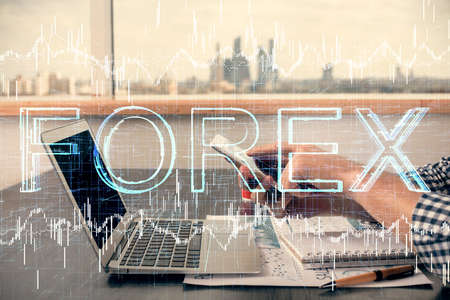 Double exposure of man's hands holding and using a digital device and forex graph drawing. Financial market concept.の写真素材