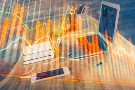 Stock market graph on background with desk and personal computer. Double exposure. Concept of financial analysis.の写真素材