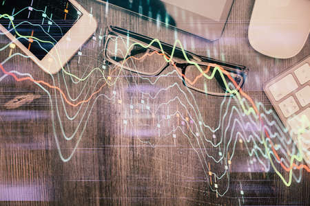 Multi exposure of forex graph hologram over desktop with phone. Top view. Mobile trade platform...