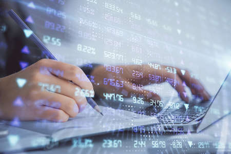 Double exposure of businesswoman hands typing on computer and forex chart hologram drawing....