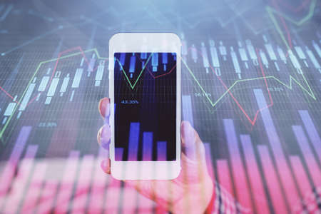 Double exposure of man's hands holding and using a digital device and forex graph drawing. Financial...