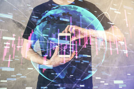 Double exposure of man's hands holding and using a digital device and forex graph drawing. Financial...